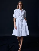 Vestido camisero blanco de algodón con cuello con solapa, delantera abotonada, mangas 3/4 regulables con presilla y botón, y cintura con lazo de ajuste.