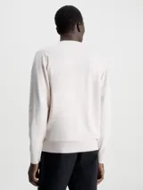 Sweater color beige de Calvin Klein, confeccionado en mezcla de tencel con elasticidad añadida. Tiene cuello redondo, puños y bajo de canalé, y etiqueta con logo de Calvin Klein por encima del bajo.