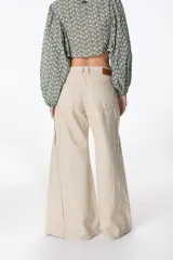 Pantalón jean color beige, de corte recto y tiro alto, con bolsillos delanteros y traseros, y detalle desflecado en los laterales.