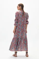 Vestido midi de lino color ladrillo con estampado floral celeste, corte recto, cuello mao, mangas abullonadas 3/4 con puños elásticos, cierre frontal con botones y falda con volantes.