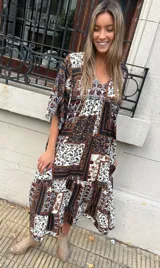 Vestido largo con estampado floral en tonos marrones, blancos y negros. Tiene escote en V, mangas cortas y corte holgado.