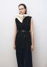 Chaleco negro con cuello pico con solapa, cierre de doble botonadura y cinturón fino.