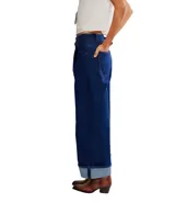 Pantalón de jean ancho de tiro alto, color azul oscuro, con pliegues pronunciados en la parte delantera y puños doblados en el ruedo.