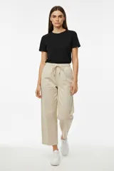 Pantalón de algodón color beige, de corte ancho y tiro alto, con cintura elástica y cordón ajustable.