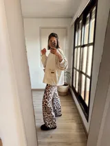 Campera oversize color crudo con mangas largas abullonadas y bolsillo frontal. Pantalón palazzo con estampado animal print.