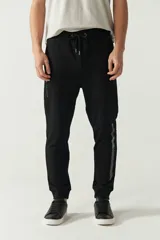 Pantalón de jogging negro de felpa con puños y cintura ajustable con cordón. Presenta logo de goma en la pierna izquierda y bolsillos laterales.
