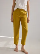 Pantalón largo de lino color marrón, con corte cigarette, tiro alto, bolsillos laterales y traseros con pespuntes a la vista, y etiqueta de cuero con logo en la cintura.