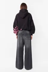 Buzo tipo hoodie negro con proceso artesanal de teñido en mangas y parte inferior. Tiene silueta boxy, puños y cintura de rib, capucha forrada y bolsillo canguro.