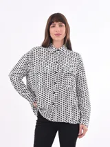 Camisa blanca estampada con motivos geométricos negros, de corte holgado, manga larga y cuello camisero.