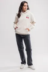 Canguro de felpa color crema, de corte oversize, con capucha y bolsillo tipo canguro. Tiene un pequeño bordado de cerezas en el pecho.