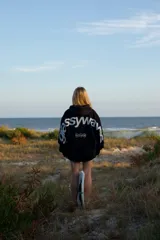 Sudadera con capucha negra, de manga larga, con estampado blanco en la espalda que dice "glassy waves" y otros símbolos.