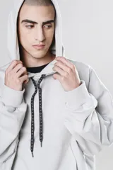 Hoodie corto color gris claro, de corte holgado, con capucha y cordones negros.
