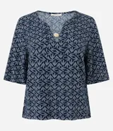 Blusa tipo bata de mangas cortas, confeccionada en viscosa con estampado de follaje en blanco sobre fondo azul marino. Tiene escote en V con detalle de abalorio en el centro.