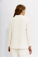 Blazer color blanco hueso, con solapas de muesca, cierre frontal con un botón y bolsillos delanteros con solapa.