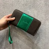 Billetera de cuero rústico color negro con detalles metalizados en azul, cierre metálico, y múltiples compartimentos para tarjetas.