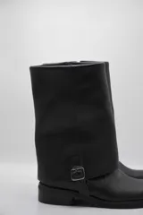 Bota de cuero color marrón oscuro con efecto desgastado, caña media, hebilla lateral y suela plana.