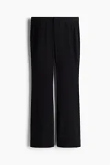 Pantalón negro de corte sastrero con cintura estándar, cierre y botón. Tiene bolsillos al bies en la parte delantera y bolsillos insertados decorativos en la parte trasera. Las piernas son acampanadas.