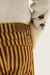 Pantalón de jean tiro medio, corte wide leg, con estampado de rayas verticales en tonos amarillo mostaza y marrón oscuro.