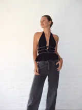 Top negro con escote halter y detalle de tachas plateadas en el busto. Tiene corte peplum y espalda descubierta.