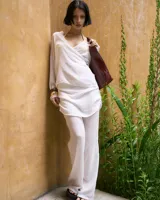 Saquito de gasa color blanco con tiras para atar y mangas largas.