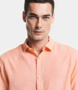 Camisa celeste de lino con cuello camisero, abotonadura frontal y mangas largas.