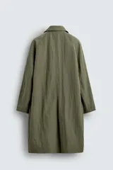 Trench color verde oliva de tejido técnico, corte relaxed fit, cuello solapa, manga larga, bolsillos laterales y abertura en la espalda.