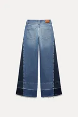 Pantalón de jean de tiro medio con cinco bolsillos, corte wide leg y detalle de tejido con lavado lateral combinado.