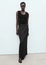 Falda larga negra de lino, con forro de algodón, cintura elástica, tiro medio, diseño lápiz, abertura en la parte posterior y cierre de cremallera lateral.