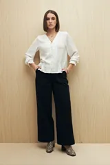 Pantalón de vestir color beige, de corte wide leg y tiro alto, con bolsillos laterales y traseros.