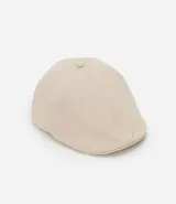 Boina color beige confeccionada en sarga de algodón, con botón en la parte superior y cierre de elástico.