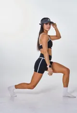 Conjunto deportivo negro con detalles en blanco, compuesto por un top con breteles finos y un short ajustado.