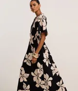 Vestido evasé midi de airflow negro con estampado de flores color crema, escote en V, sisa alargada, mangas cortas amplias y lastex en la cintura.