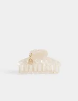 Broche para el pelo tipo pinza, color crema con efecto marmolado y charm colgante dorado con forma de trébol de cuatro hojas.