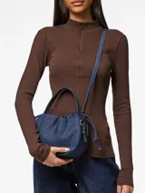 Bolso tipo bombonera confeccionado en denim azul, con asa superior y correa ajustable y desmontable.