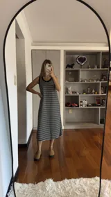 Vestido largo sin mangas, ajustado al cuerpo, con cuello redondo y estampado de rayas horizontales blancas y negras.