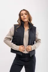 Chaleco puffer negro de corte cropped, con cierre frontal y cuello alto.