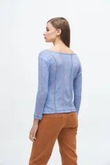 Remera gris de corte ajustado, con cuello redondo y mangas largas. Presenta líneas verticales bordadas en color verde claro y blanco.