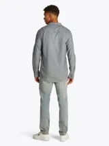 Camisa de manga larga Tommy Jeans, confeccionada en algodón y lino color gris jaspeado. Tiene cuello abotonado, cierre con botones, corte regular y logo bordado en el pecho.