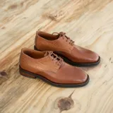 Zapato acordonado de cuero color marrón con detalle de textura reptil en el talón y empeine. Taco de madera foliado en cuero de 2,5 cm de altura y entre suela de goma de 1 cm.