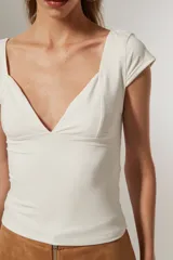 Top blanco de manga corta, ajustado al cuerpo y con escote profundo en V.
