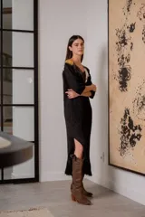Vestido negro de noche con mangas 3/4, cuello en V con detalles de cuero entrelazado, terminación en flecos y tajos laterales.