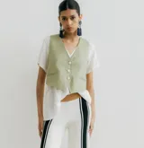 Chaleco corto color verde claro, confeccionado en lino, con cuello en V y cierre frontal con tres botones.