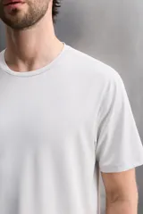 Camiseta deportiva de entrenamiento, corte regular fit, color gris claro, con cuello redondo y manga corta. Confeccionada en tejido técnico ligero y elástico con estructura Quick Dry nivel 2. Presenta costuras planas y un pequeño logo estampado en la parte inferior derecha.