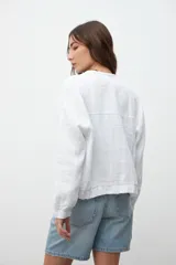 Chaqueta bomber blanca de lino con cuello redondo, cierre frontal con botones y mangas largas.