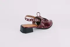 Sueco de cuero negro con cordones, ojales, hebillas y tira trasera regulable con elástico. Tiene taco cuadrado bajo.