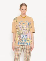 Remera color beige con estampado de figura humana con flores y objetos decorativos.
