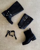 Bota de cuero negra, desmontable 3 en 1, con detalle de arnés con aros metálicos y hebillas.