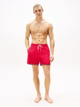 Short de baño rojo con cintura elástica ajustable con cordón blanco. Tiene dos bolsillos laterales y un bolsillo trasero de parche. El bajo presenta una franja con los colores azul marino, blanco y rojo.
