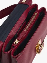 Cartera rectangular de piel sintética granulada color rojo oscuro (vino/borgoña) con solapa frontal y cierre de pinza. Presenta herrajes metálicos dorados y un broche central con el monograma TH. Incluye una correa tejida ajustable y extraíble, y una correa corta adicional.