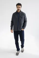 Camisa tipo chaqueta color gris oscuro, de manga larga, con cuello clásico, cierre frontal con botones a presión, bolsillo de parche en el pecho y corte recto.